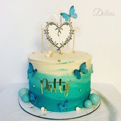 there is a blue cake with butterflies on it and the word pittty written in gold