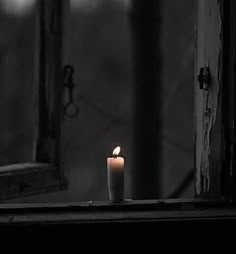 a lit candle sitting on top of a window sill next to an open door