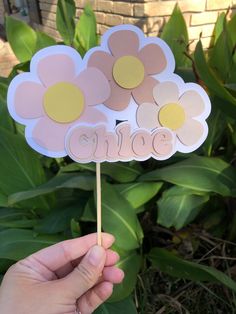 a hand holding a flower shaped cake topper with the word love spelled on it