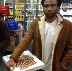 a man holding a pizza box in a store