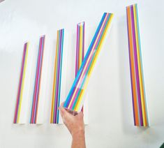 someone is holding up some colored straws on the wall and pointing them at each other