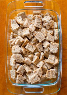 a glass dish filled with tofu cubes on top of a wooden table