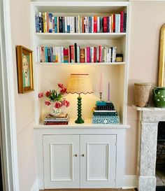 a white bookcase filled with books next to a fireplace