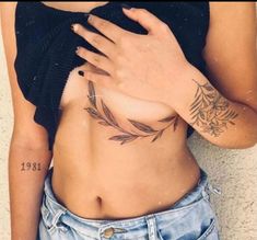 a woman's stomach with tattoos on it and her hand resting on the belly