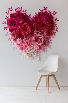 a white chair sitting in front of a heart shaped wall with pink flowers on it