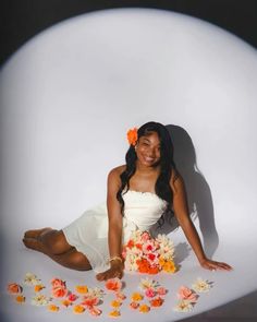 a woman sitting on the ground with flowers in front of her and posing for a photo