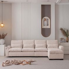 a living room with a white couch and pillows on the floor next to a mirror