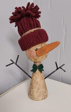 a wooden snowman with a red hat and green scarf on it's head