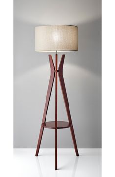 a lamp that is sitting on top of a wooden stand with a white shade over it