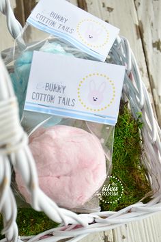 some cotton balls are in a basket on the ground with grass and tags attached to them