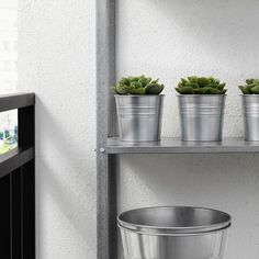 three potted plants sitting on top of metal shelves