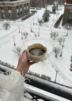 someone is holding up a small bowl in the snow