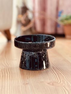 a black candle holder sitting on top of a wooden table