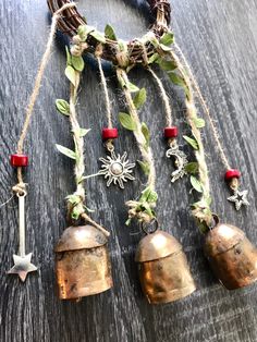 three bells hanging from a rope on top of a wooden table next to a wreath