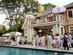 a group of people standing in front of a house with umbrellas over their heads