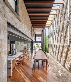 a long wooden table sitting in the middle of a room next to a brick wall