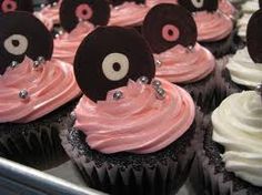 cupcakes with pink frosting and black decorations on top are arranged in rows