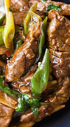 beef and peppers stir fry on top of rice in a black plate with chopsticks