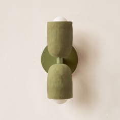 two green vases are on the wall next to each other and one is holding a white ball