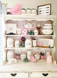 a white shelf filled with dishes and cups