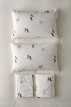 three pillows and two pillow cases on top of each other with black cats printed on them