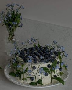 a white cake with blue flowers and greenery on top