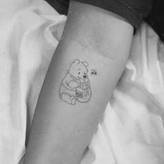 a black and white photo of a winnie the pooh tattoo on someone's arm