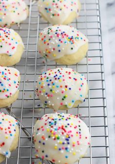 white frosted cookies with sprinkles on a cooling rack