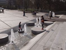 people are walking around in the park with fountains