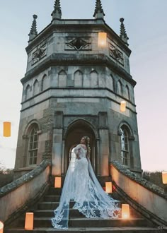 a woman in a wedding dress standing on the steps of a building with candles around her