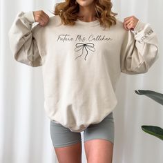 a woman is posing with her hands on her hips, wearing a sweatshirt and shorts