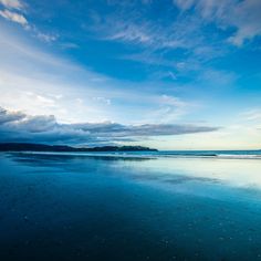 the sky is reflected in the wet sand