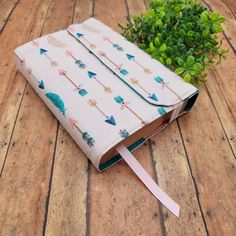 a small notebook with an umbrella pattern on it sitting on a wooden table next to a plant