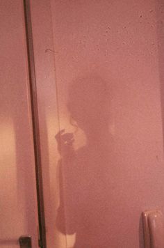 the shadow of a person standing in front of a bathroom mirror holding a cell phone