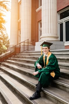 a young man sitting on steps wearing a green graduation gown