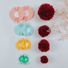 four different colors of pom poms on a white surface next to some flowers