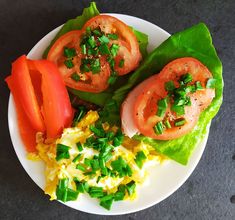 a white plate topped with lettuce, tomatoes and other food on top of it