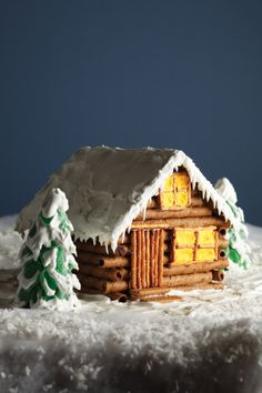 a gingerbread house with icing and pine trees on the outside is made to look like it has been frosted