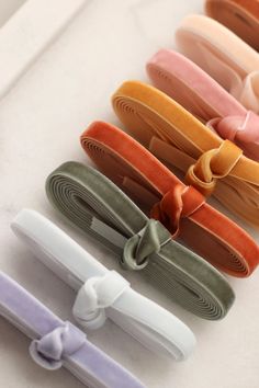 several colors of hair clips with bows on them are lined up against a white surface