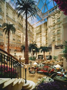 a hotel lobby filled with lots of furniture and palm trees in the middle of it