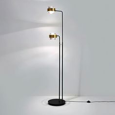 a black floor lamp with three lights on it and a white wall in the background