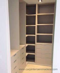 an empty walk in closet with white drawers