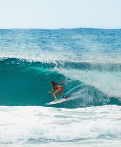 a woman riding a wave on top of a surfboard in the middle of the ocean