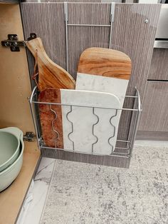 a kitchen with marble counter tops and wooden cutting boards in a metal basket next to a sink