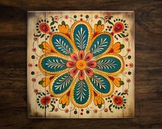 a wooden wall hanging with an intricately painted flower design on the front and side