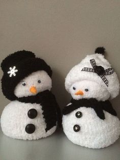 two snowmen wearing hats and scarves are sitting on a table next to each other