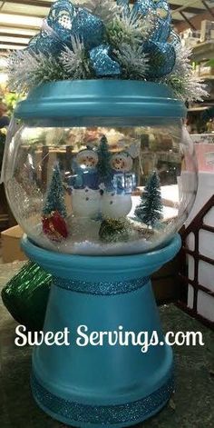 a blue snow globe with christmas decorations on top in front of a store display case