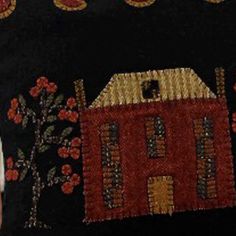 a black pillow with a red house on the front and yellow flowers on the back