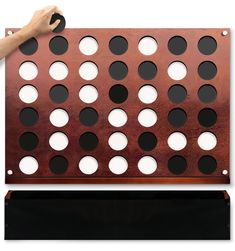 a large metal board with holes on it and a person's hand holding the board