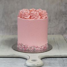 a pink cake with sprinkles and frosting on a silver platter